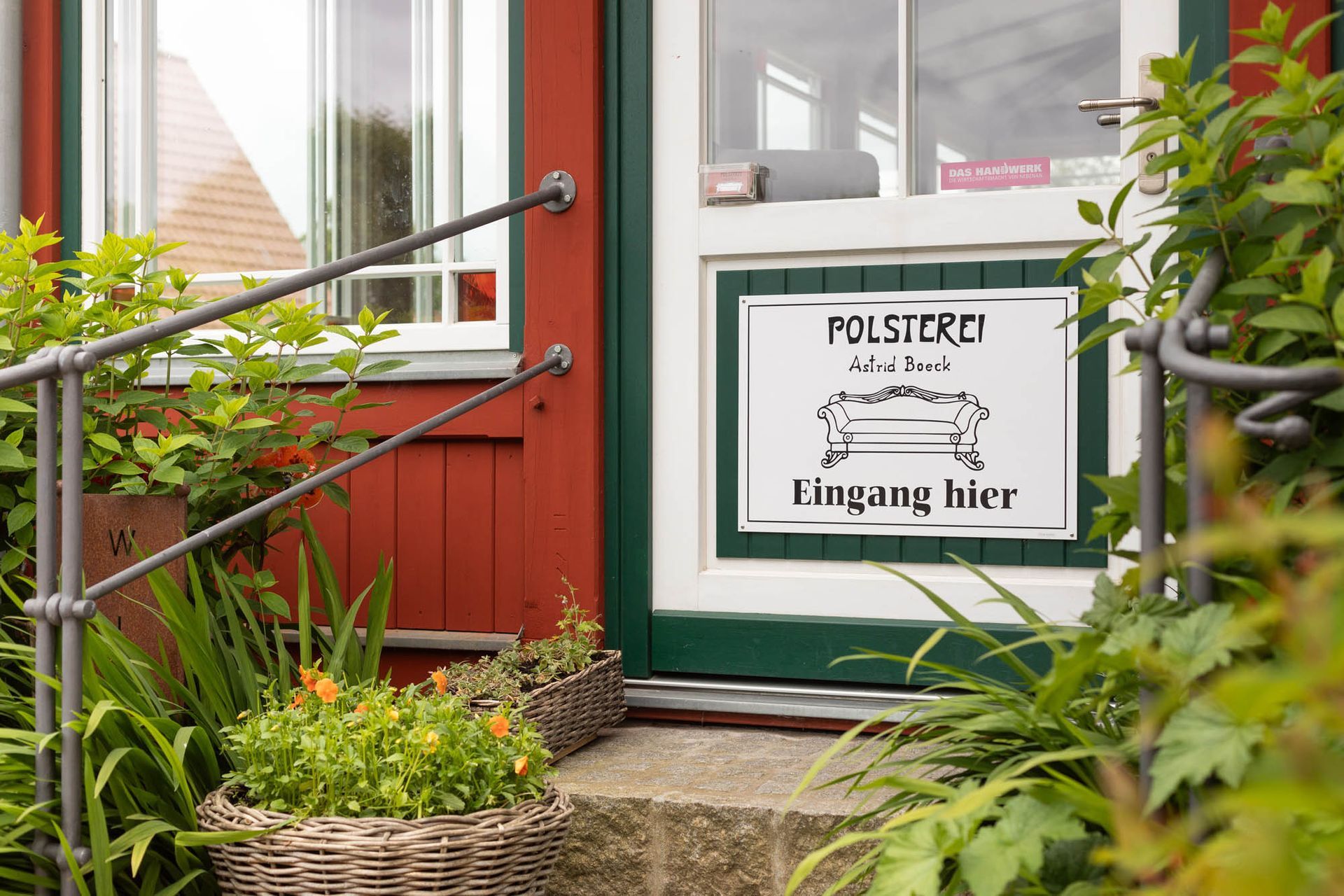 Ein rot-grünes Haus mit einem Schild an der Tür mit der Aufschrift „Eingang hier“.