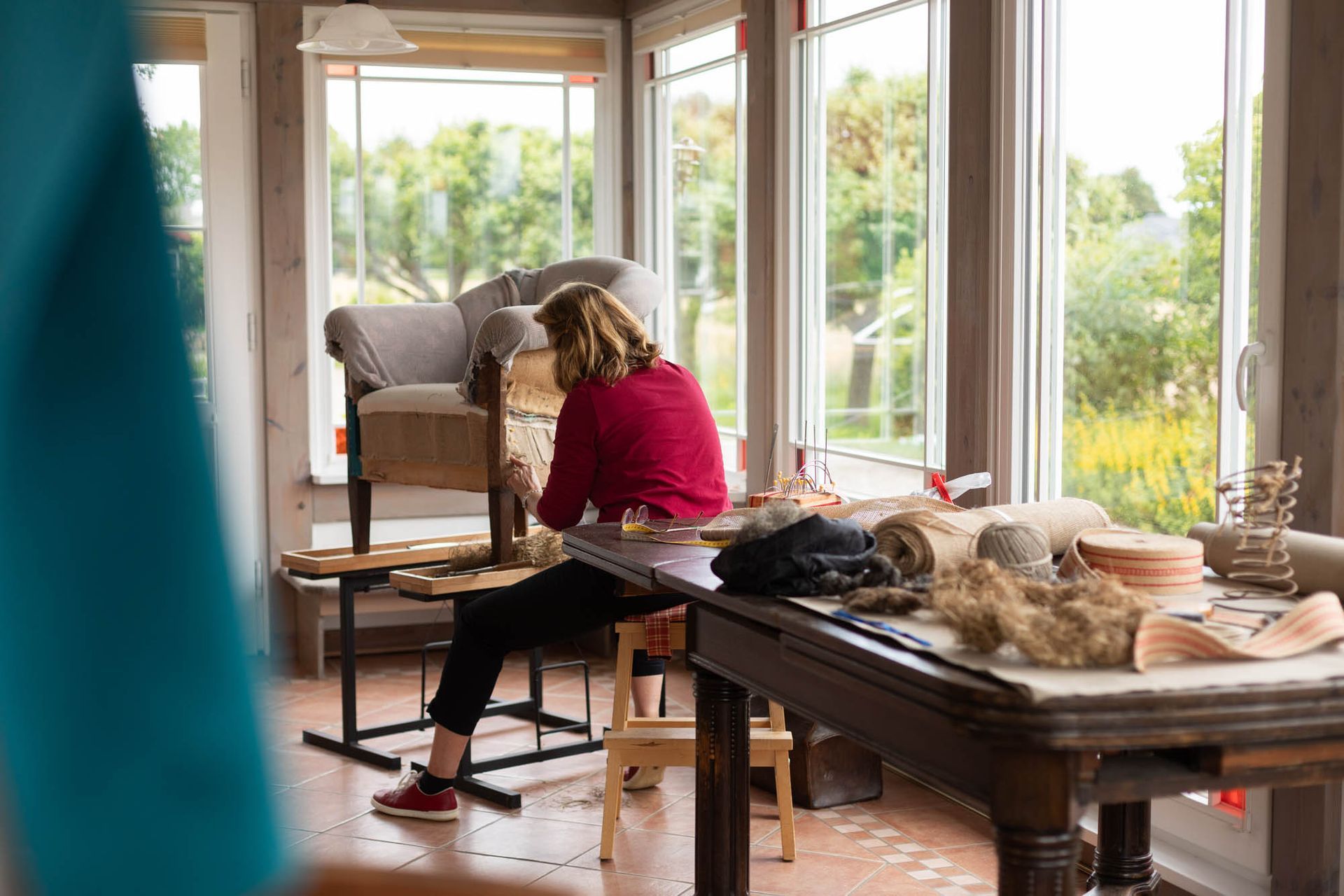 Eine Frau sitzt in einem Zimmer an einem Tisch vor einem Fenster.