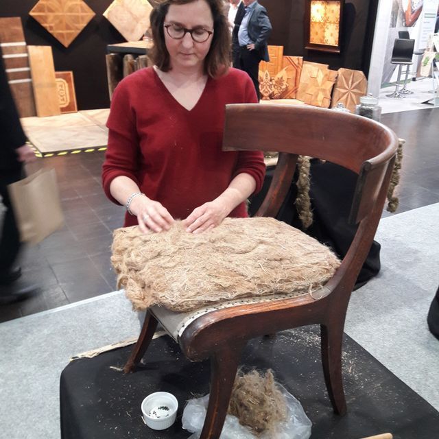 Eine Frau im roten Pullover arbeitet an einem Stuhl