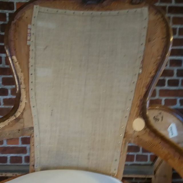 Die Rückenlehne eines Stuhls mit einer Ziegelmauer im Hintergrund