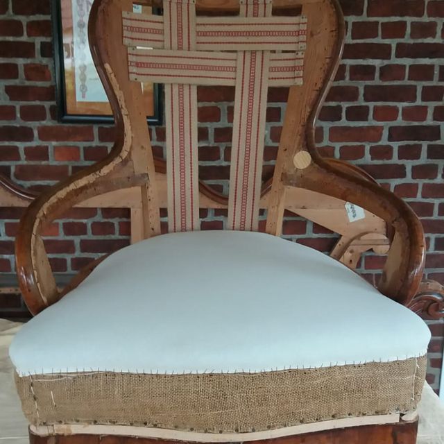 Ein Stuhl mit einem weißen Kissen steht vor einer Backsteinmauer