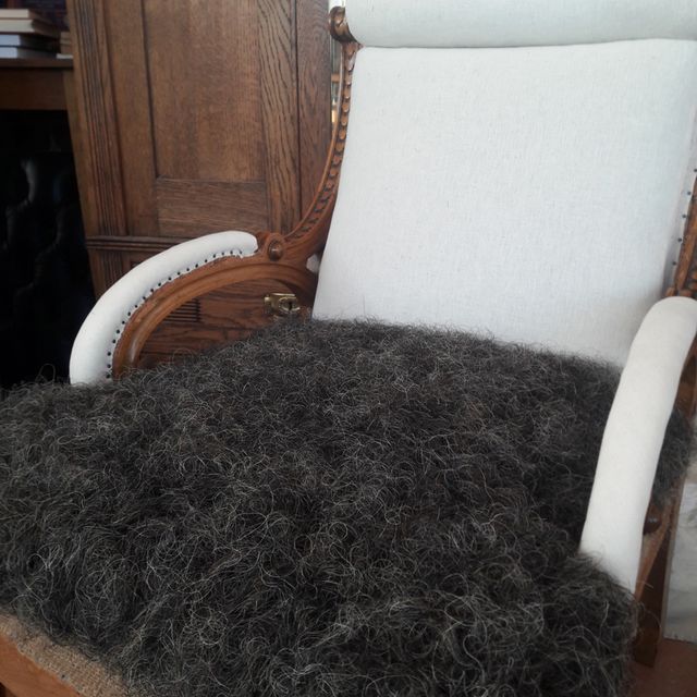 Ein Stuhl mit einem weißen Kissen und einem braunen Kissen