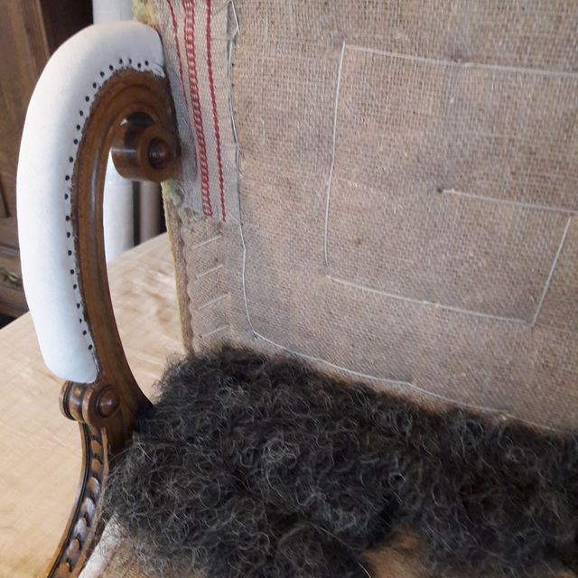 Ein Stuhl mit weißer Armlehne steht auf einem Holztisch