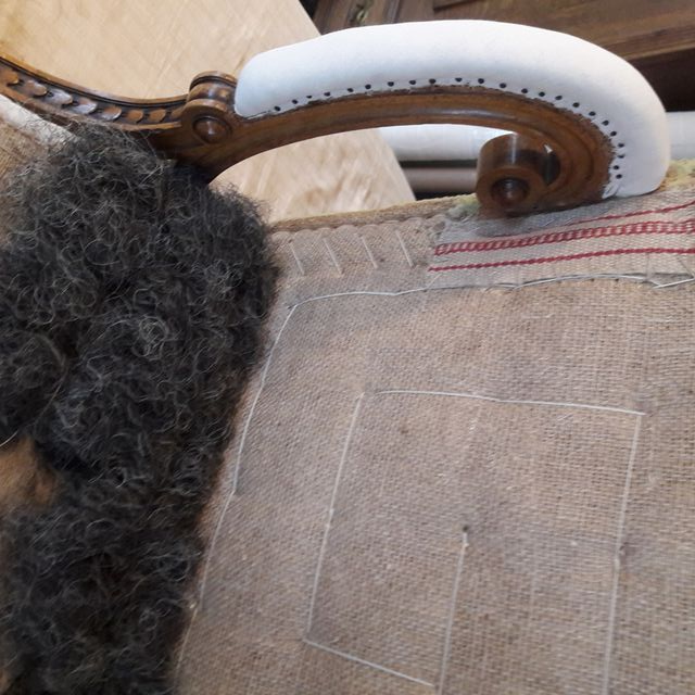 Ein Stuhl mit weißer Armlehne steht auf einem Holztisch