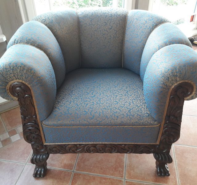 Ein blauer Stuhl mit Holzrahmen steht auf einem gefliesten Boden.