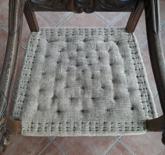 Ein Stuhl mit einem Kissen darauf steht auf einem gefliesten Boden