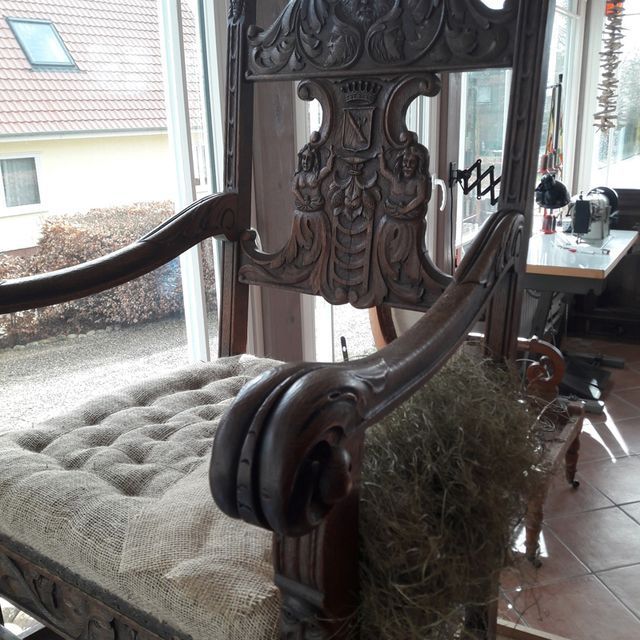 Ein Holzstuhl mit Kissen vor einem Fenster