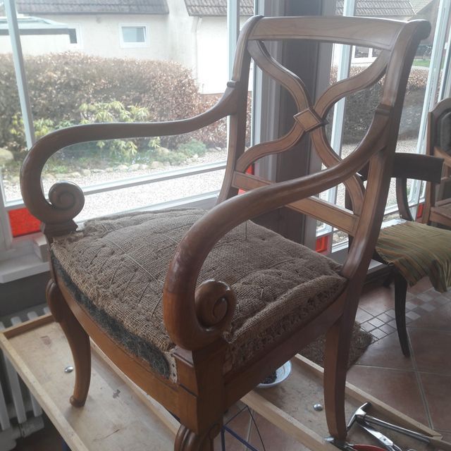 Ein Holzstuhl steht auf einem Holzregal vor einem Fenster