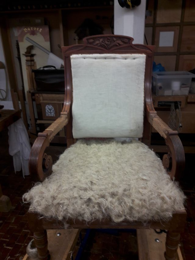 Ein Stuhl mit einem weißen Kissen steht auf einem Tisch in einem Zimmer.