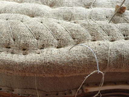 Eine Person näht ein Stück Stoff mit Nadel und Faden.