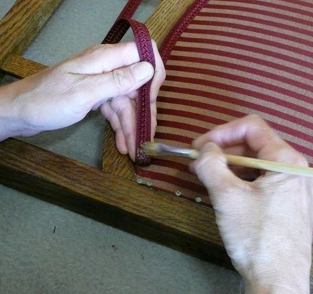 Eine Person bearbeitet einen Stuhl mit einer Bürste