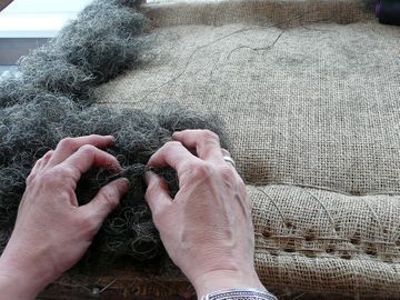 Eine Person bearbeitet ein Stück Stoff mit den Händen.