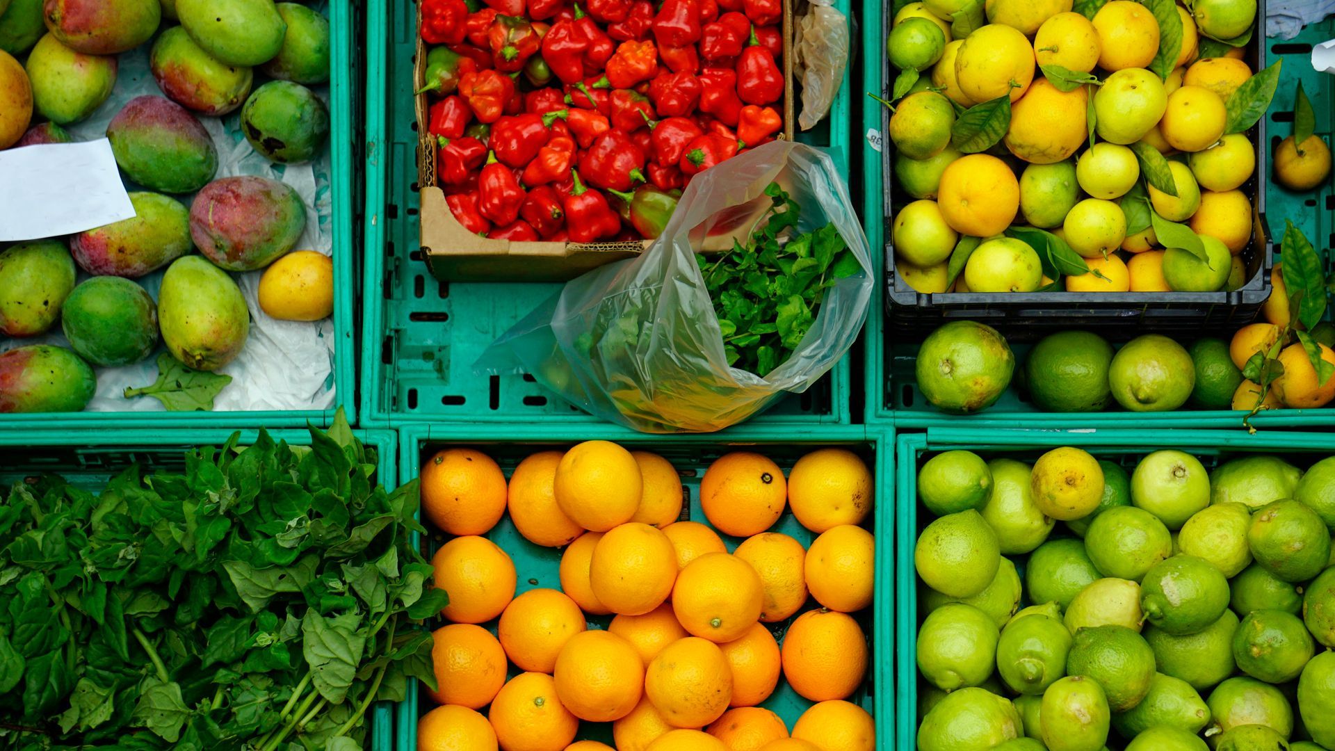 Una variedad de frutas y verduras se exhiben en cajas sobre una mesa.