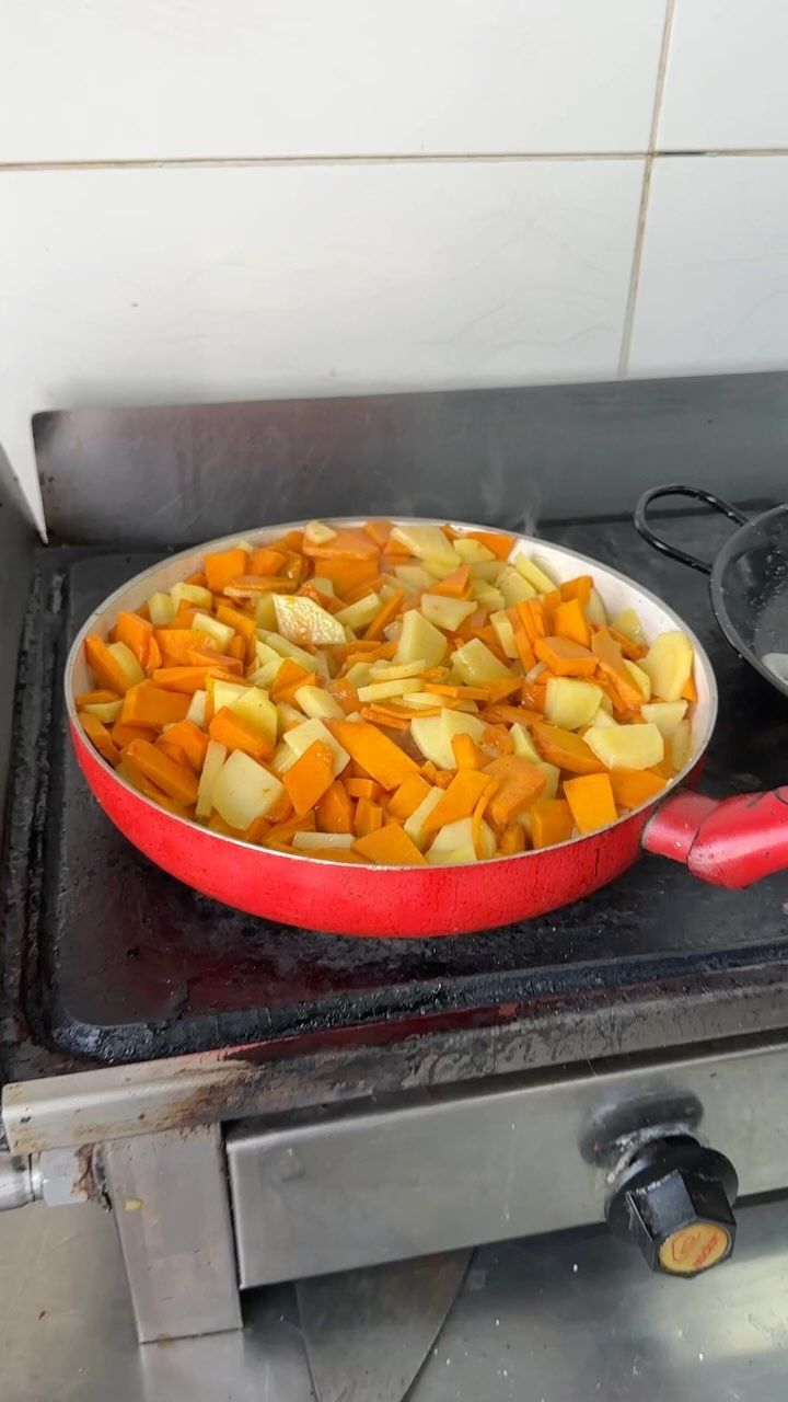 Una sartén con verduras se está cocinando en una estufa.