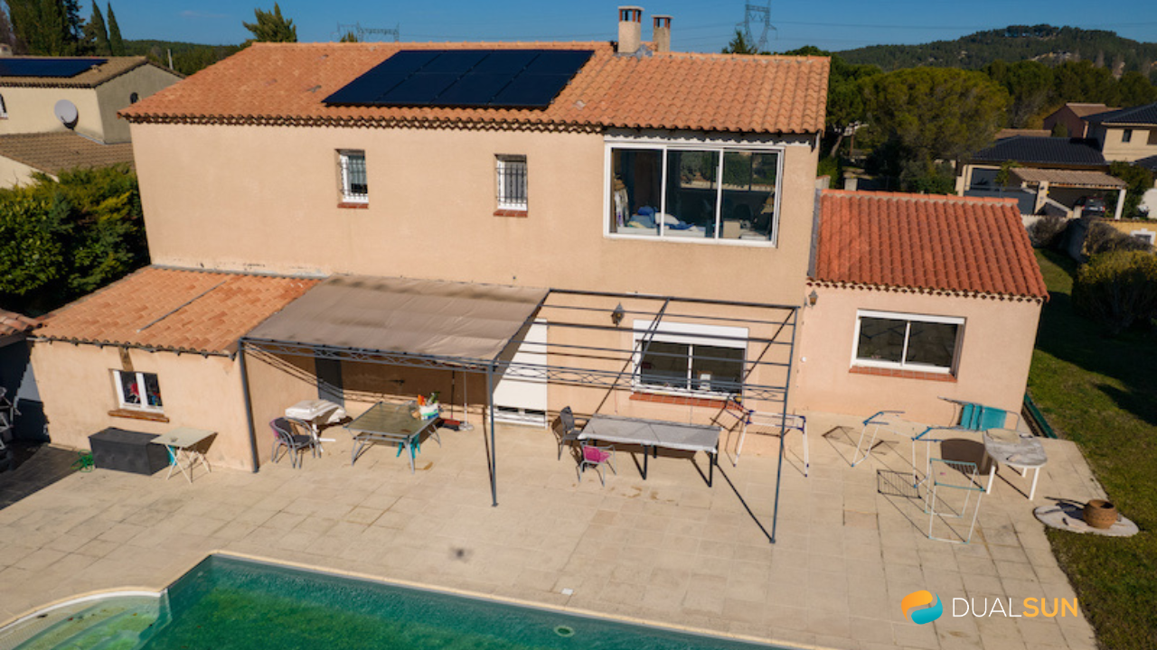 Photo d'une maison rose avec pergola et piscine, vue aérienne avec des panneaux photovoltaïques sur le toit