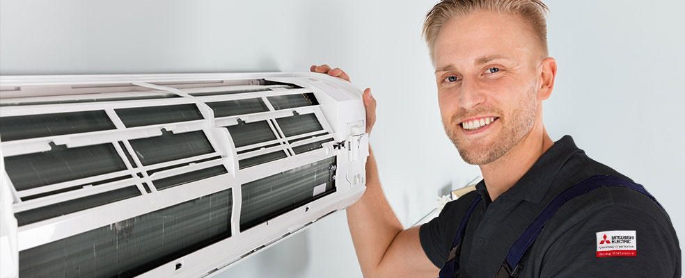 Technicien souriant à coté d'une climatisation