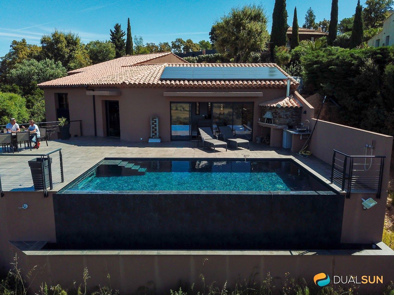 Photo d'une maison vue du sol avec des panneaux photovoltaïques sur le toit et une piscine devant