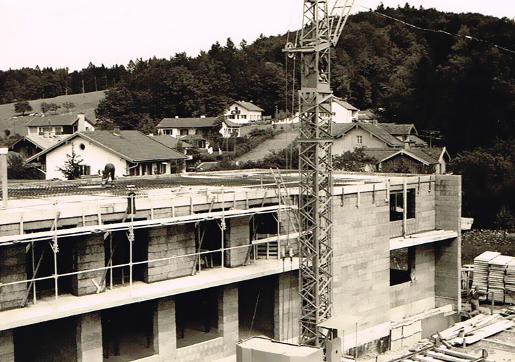 ein Schwarz-Weiß-Foto einer Baustelle mit einem Kran und Häusern im Hintergrund