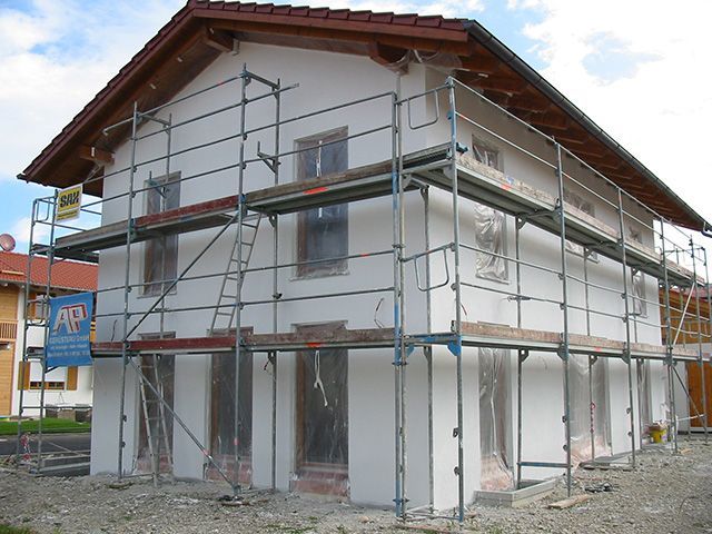 ein Haus , das mit Gerüst umgeben ist und ein Schild darauf steht