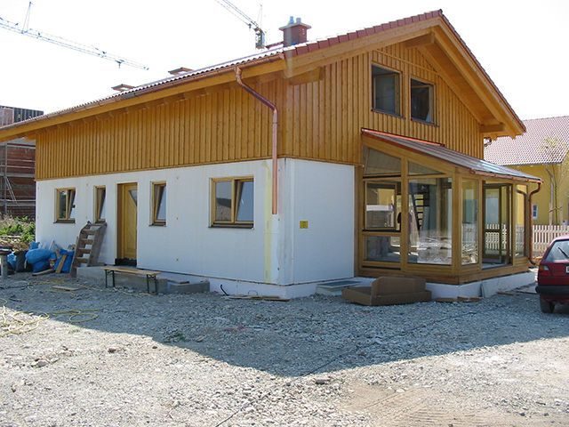 ein rotes Auto steht vor einem Haus , das im Bau ist