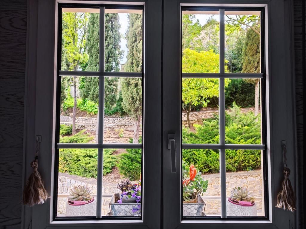 Ventana con marco blanco con vista a un exuberante jardín verde con árboles y arbustos.
