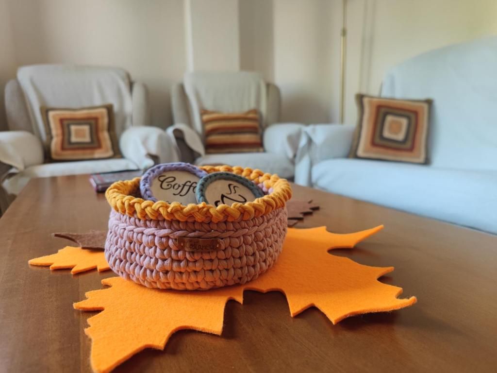 Cesta de crochet con posavasos de café sobre una mesa, decoración con temática otoñal.
