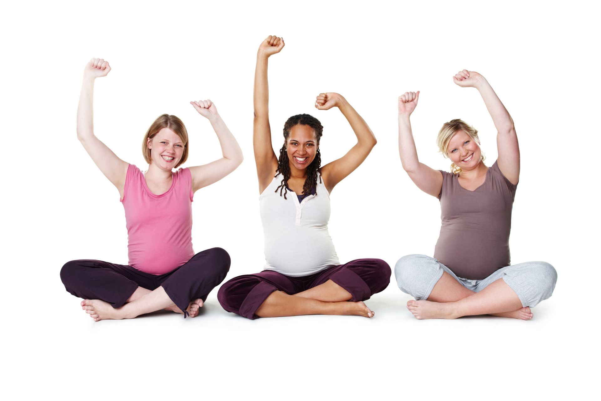 Tres mujeres embarazadas sentadas con las piernas cruzadas, levantando los brazos en señal de celebración, sonriendo; fondo blanco.