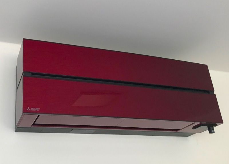 Rote Klimaanlage von Mitsubishi, an einer weißen Wand montiert.