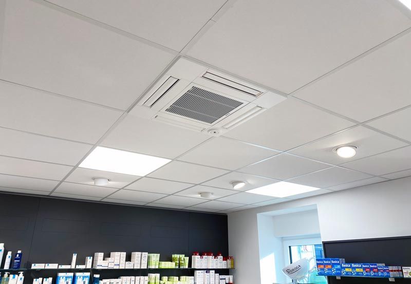 Weiße abgehängte Decke mit eingebauter Klimaanlage und Einbauleuchten in einem Geschäft.