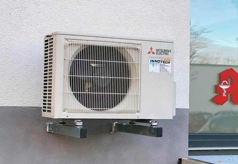 Eine außen an einem Gebäude montierte Klimaanlage. Die Einheit ist weiß und grau.