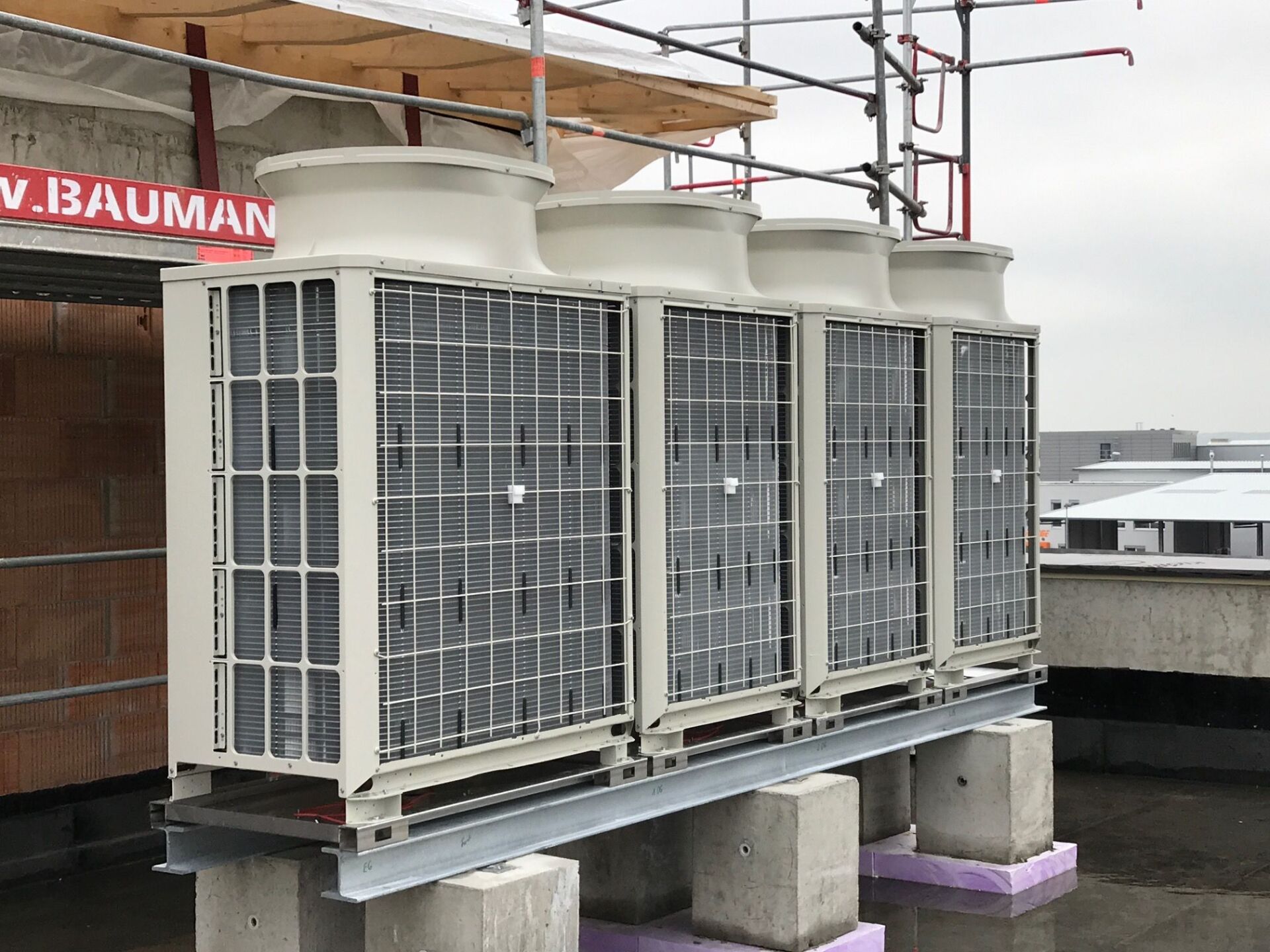 HVAC-Einheiten auf einem Dach, mit Gerüst in der Nähe, an einem bewölkten Tag.