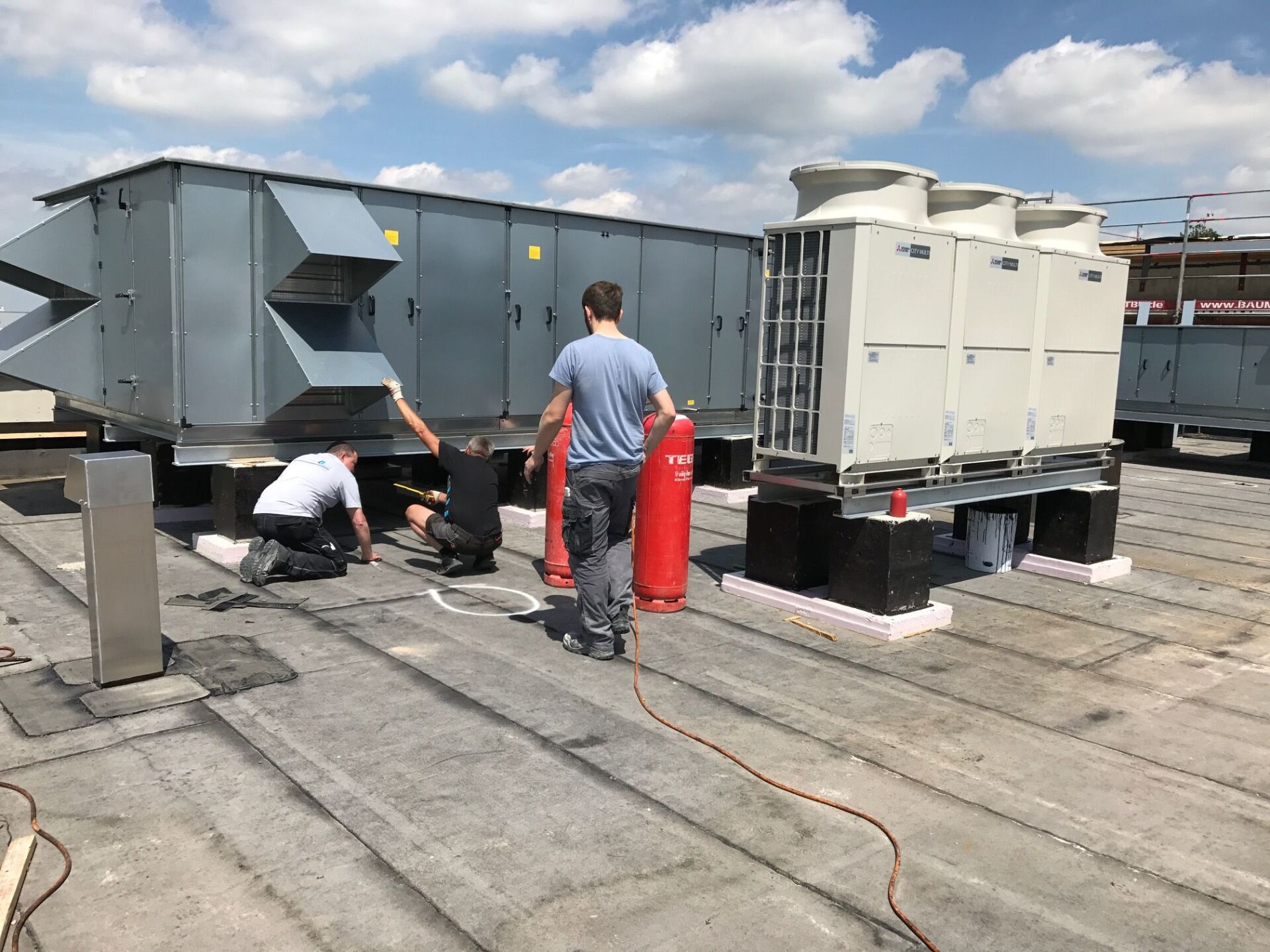 Männer arbeiten an HLK-Anlagen auf dem Dach.