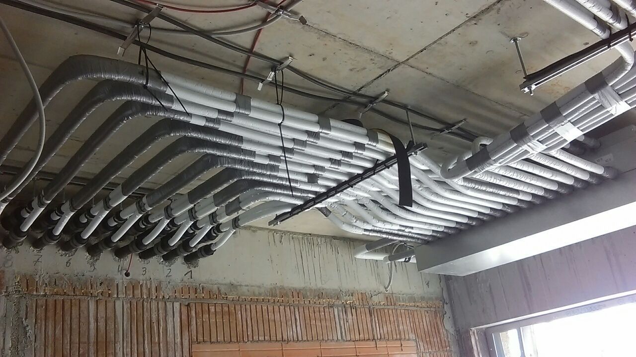 Elektrische Leitungen und Kabel, die an einer Betondecke auf einer Baustelle befestigt sind.