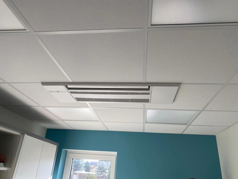 Weiße Decke mit Einbauleuchten, quadratischen Fliesen und einer blaugrünen Wand.