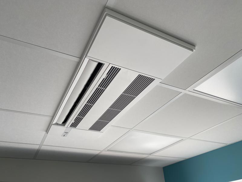 An der Decke montierte Klimaanlage mit Lüftungsöffnungen, eingebaut in ein abgehängtes Deckengitter.