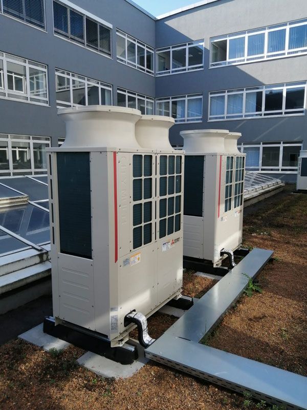 Zwei große Klimaanlagen auf einem Dach in der Nähe von Fenstern.