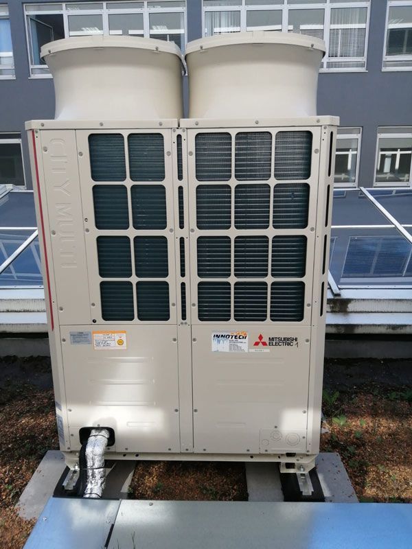 Zwei beigefarbene Klimaanlagen von Mitsubishi auf einem Dach.