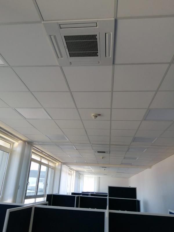 Bürodecke mit Klimaanlage, Beleuchtung und Kabinen. Farben: Weiß und Schwarz.
