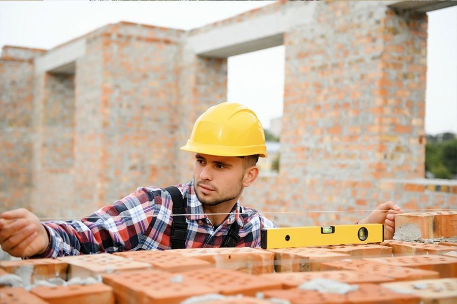 Un trabajador de la construcción está midiendo ladrillos con un nivel.