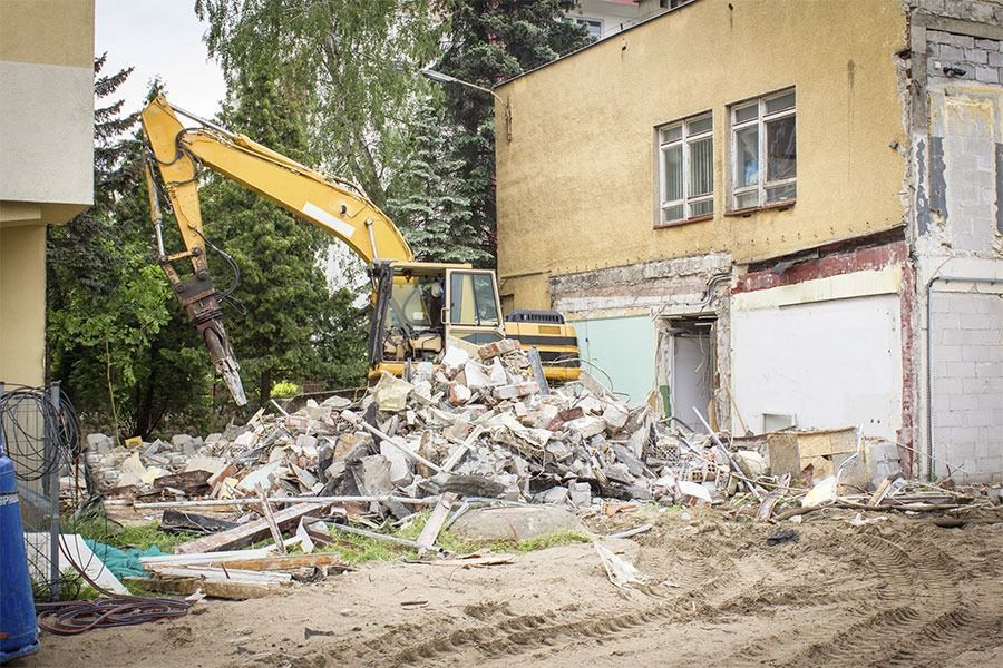 Una gran excavadora amarilla está demoliendo un edificio.