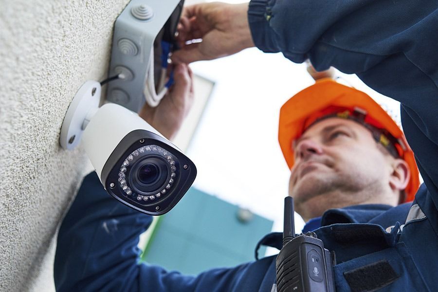 Un hombre está instalando una cámara de seguridad en una pared.