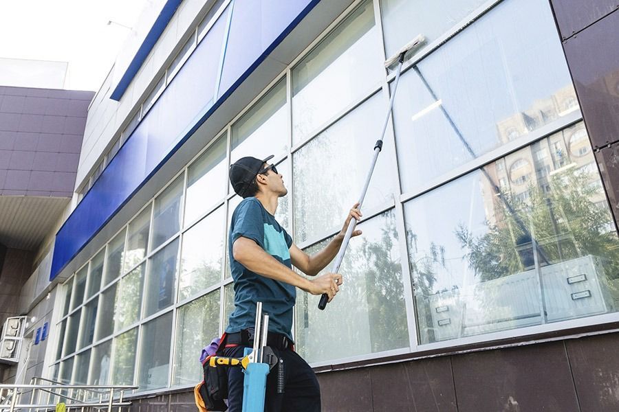 Un hombre está limpiando las ventanas de un edificio con una escobilla de goma.