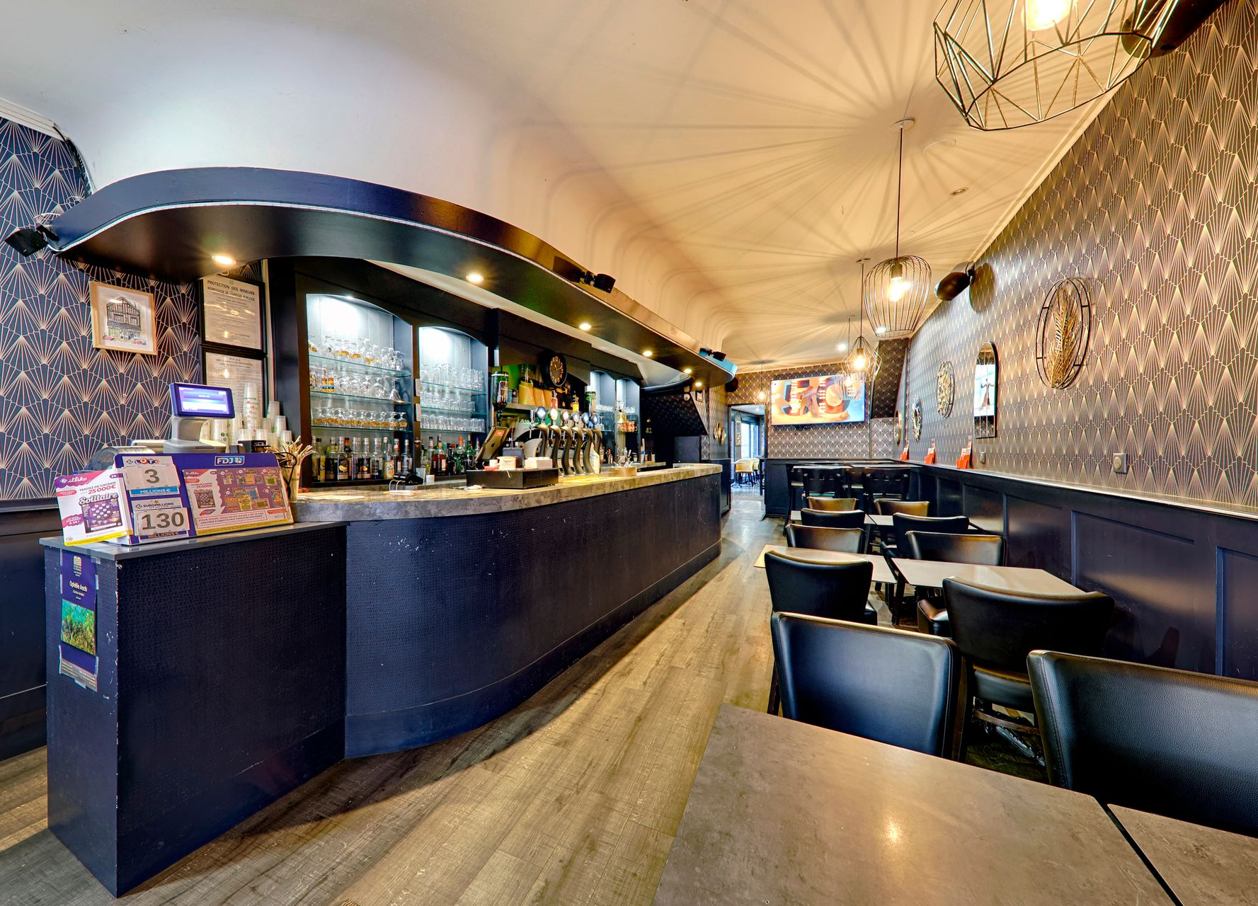 Vue intérieure d'un bar avec des murs bleus, des tables et un comptoir incurvé.