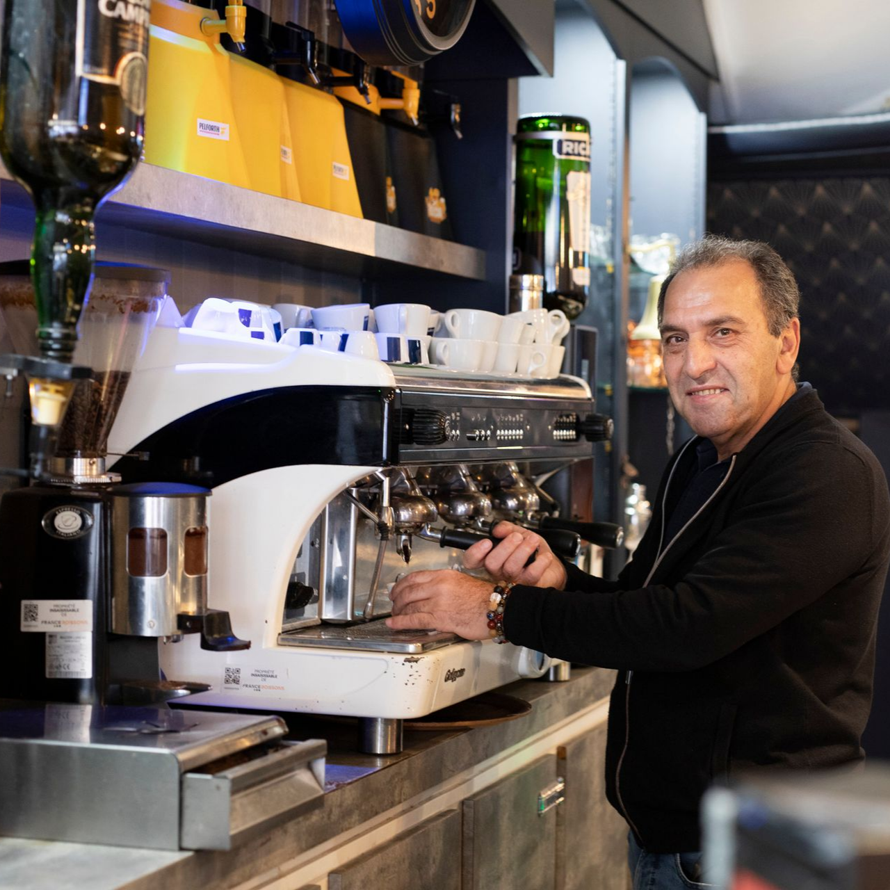Un homme souriant qui prépare du café avec une machine.