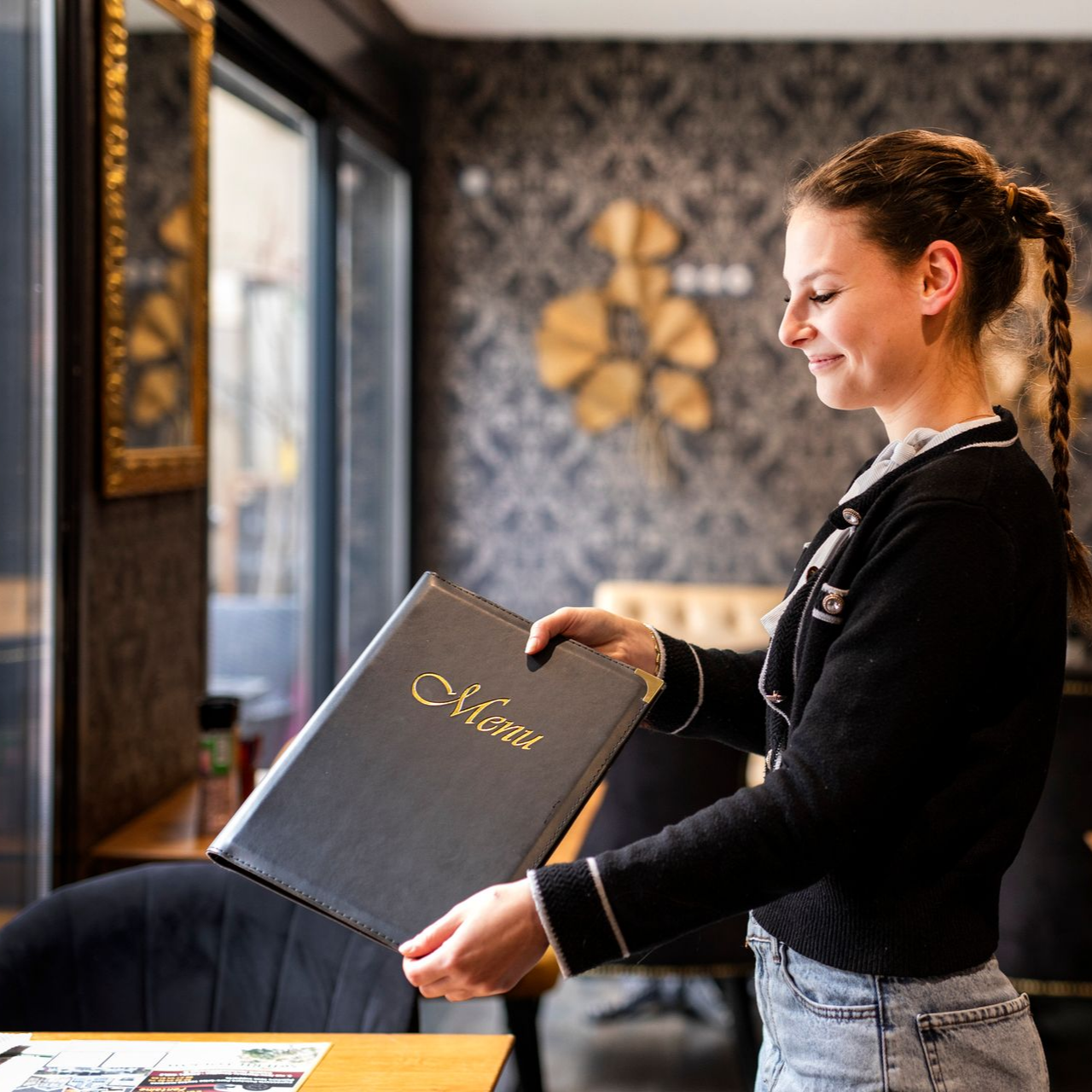 Serveuse souriant tenant un menu dans un restaurant.