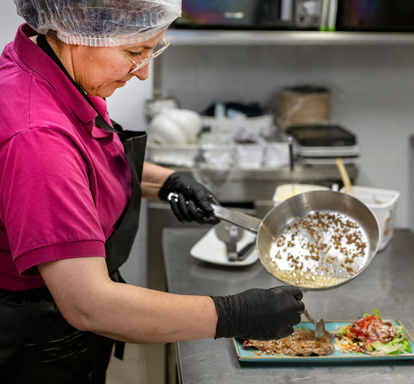 Une femme et un homme lisent un menu à table, deux verres de vin rouge avec une bougie allumée.