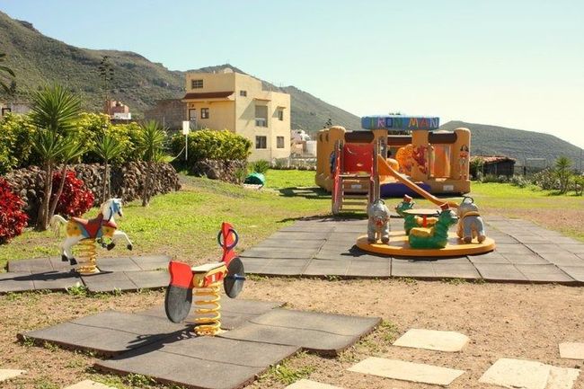 Un parque infantil con una casa inflable al fondo