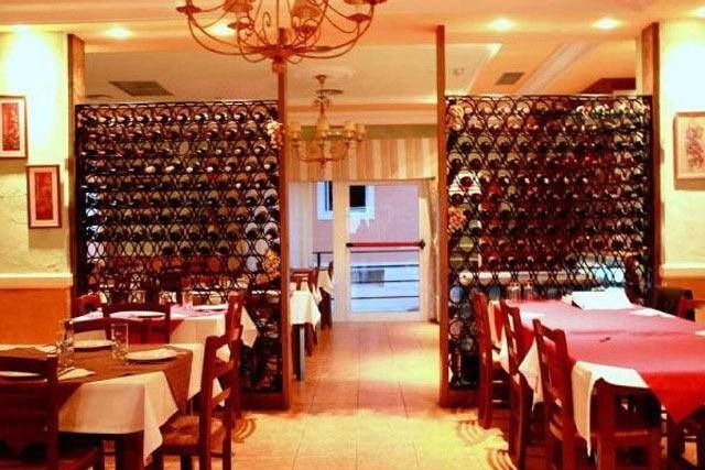 Un restaurante con mesas y sillas y una pared de botellas de vino.