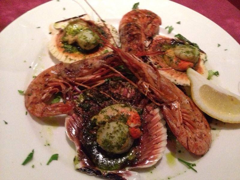 Un plato blanco cubierto con vieiras de camarones y rodajas de limón.