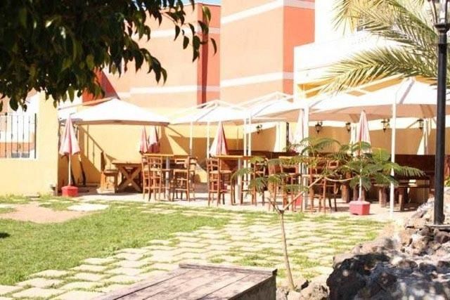 Un área de patio con mesas y sombrillas frente a un edificio.